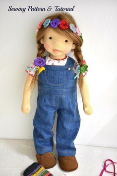 a doll is wearing overalls and a flower headband next to a crocheted hat