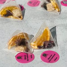 four pieces of fruit wrapped in plastic sitting on top of a white tablecloth covered with pink stickers