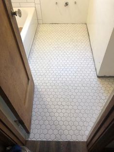 an empty bathroom with white tile and wood cabinets in the corner, looking down at the floor