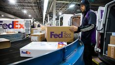 a fed ex worker unloading boxes from the back of a truck in a warehouse