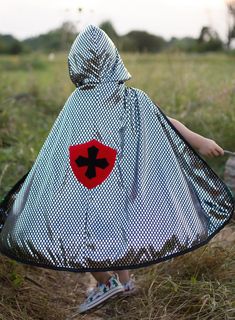 a person wearing a hooded cloak in a field