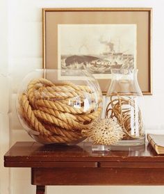 a rope ball sitting on top of a wooden table next to a framed photo and lamp