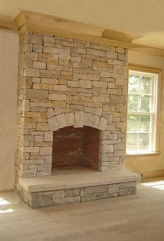 an empty room with a stone fireplace in the center and two windows on either side