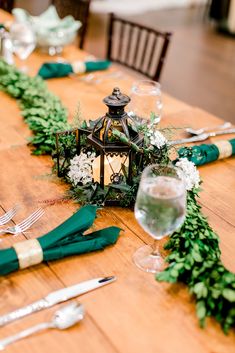 the table is set with green napkins, silverware and greenery on it