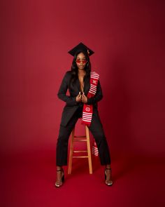 a woman sitting on top of a stool wearing a graduation hat and holding an american flag