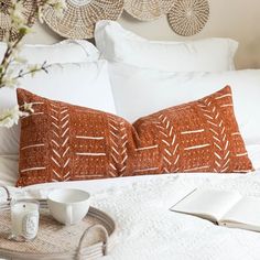 a white bed topped with pillows next to a tray filled with cups and saucers