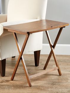 a wooden table sitting on top of a hard wood floor next to a white chair