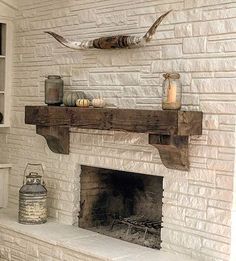 a white brick fireplace in a living room next to a shelf with candles on it