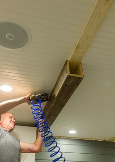 a man working on a ceiling with blue hoses attached to the underside of it