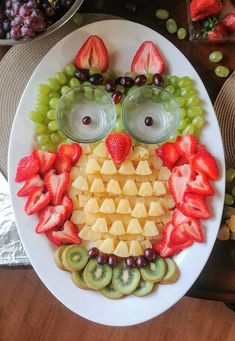 a white plate topped with fruit and an owl made out of grapes, strawberries, kiwis