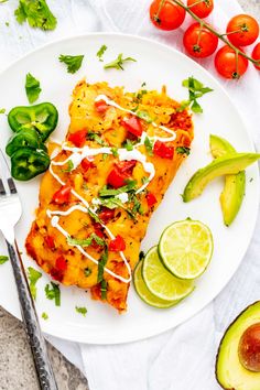 a white plate topped with mexican food next to sliced avocado and limes