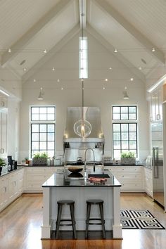 a large kitchen with two stools in front of the center island and an open floor plan