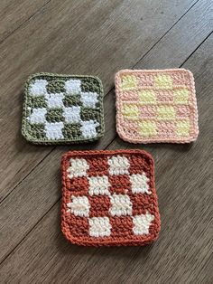 three crocheted squares sitting on top of a wooden floor next to each other