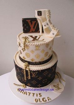 a three tiered cake decorated with louis vuitton shoes and purses on top