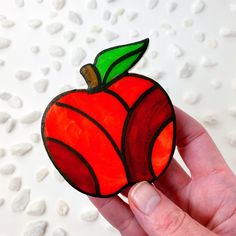 a hand holding up a stained glass apple