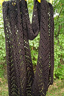 a crocheted shawl hanging on a clothesline in the grass with trees in the background