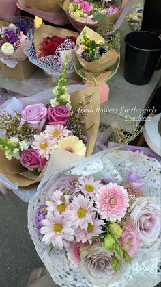 several bouquets of flowers are sitting on the ground next to each other in brown paper bags