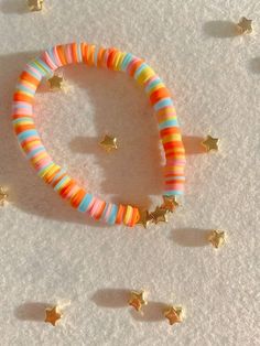 an assortment of colorful bracelets and star studded earrings on a white surface with gold stars