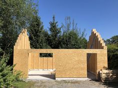 a house being built in the middle of a forest with trees and bushes around it