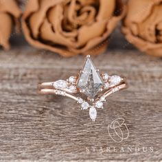 an engagement ring with a pear shaped cut diamond surrounded by smaller round diamonds and rose petals