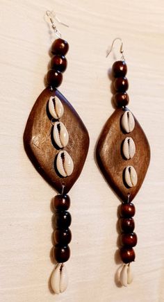 These are so beautiful and unique Extra large style These hang 7 inches Light on the ear Handmade original design Made with large and chunky wooden Earrings and authentic cowrie shells One of a kind Sure to get attention and compliments Handmade Brown Cowrie Shell Jewelry, Bohemian Brown Cowrie Shell Jewelry, Wood Beads Jewelry, Cowrie Shell Earrings, Cowrie Shell Jewelry, Cowrie Shells, Cowrie Shell, Shell Jewelry, Wooden Earrings