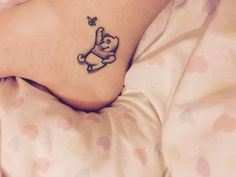 a small tattoo on the foot of a person with a teddy bear holding a butterfly