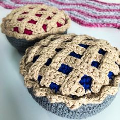 two crocheted cupcakes sitting next to each other on top of a table