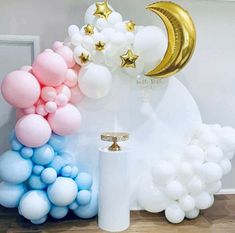 balloons, stars and moon are arranged on the wall in front of a white pillar