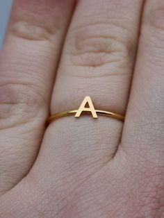 This elegant gold initial ring is perfect for stacking, making it a great gift for any occasion - whether a mother's day surprise or a best friend's birthday present. Crafted from quality stainless steel, this letter ring will look beautiful for years to come. Featuring a letter of your choosing, this ring can be worn alone or stacked making it perfect for gifting to friends or family. The subtle, yet sweet letter ring looks elegant alone or as part of a larger stack. This gold letter ring is th Everyday Gold Stackable Rings With Initials, Gold Stackable Rings With Initials For Everyday, Simple Anniversary Rings With Initials, Simple Anniversary Ring With Initials, Simple Yellow Gold Initial Ring For Anniversary, Dainty Gold Stackable Rings With Initials, Simple Personalized Gold Stackable Rings, Modern Tan Jewelry For Gift, Modern Tan Jewelry For Gifts