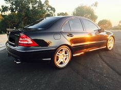 a black car parked in a parking lot with the sun shining on it's side