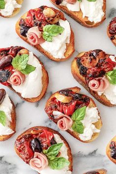 several pieces of bread with various toppings on them sitting on a marble counter top