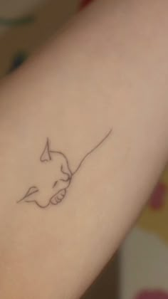 a small tattoo on the arm of a woman with a cat's head drawn on it