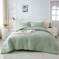 a bed with green comforter and pillows in a room