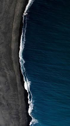 an aerial view of the ocean and black sand beach