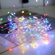 an open laptop computer sitting on top of a table covered in christmas lights