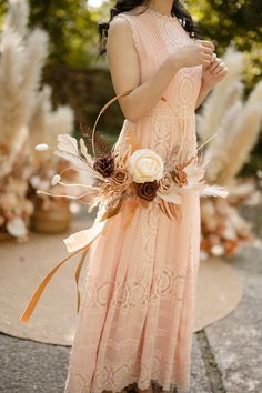 a woman in a pink dress with flowers on her head and an orange ribbon around her neck