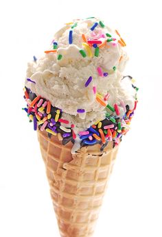 an ice cream cone filled with sprinkles and white frosting on top