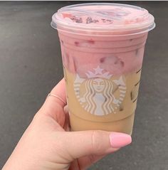 a hand holding up a starbucks drink in front of a car