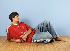 a young man laying on the floor wearing a red shirt