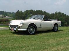 an old white sports car is parked in the grass