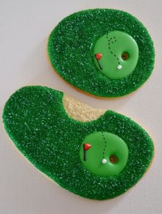 two decorated cookies with green frosting and golf balls on them, one has a hole in the middle