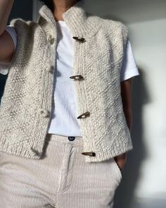 a woman is wearing a white sweater and vest