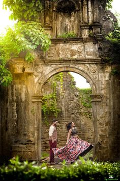 a man and woman standing in front of an old building with ivy growing on it