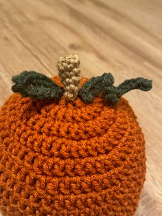 an orange crocheted pumpkin sitting on top of a wooden floor