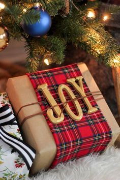 a christmas tree with presents under it and the word joy written in gold on top