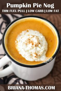 a white cup filled with whipped cream on top of a brown and black table cloth