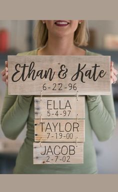 a woman holding up a wooden sign with names on it