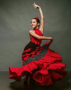 a woman in a red and black dress is dancing with her arms out to the side