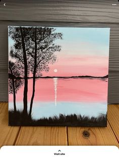 a painting on a wooden table with a tree in the foreground and a pink sky