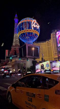 a taxi cab is parked in front of the eiffel tower and neon signs